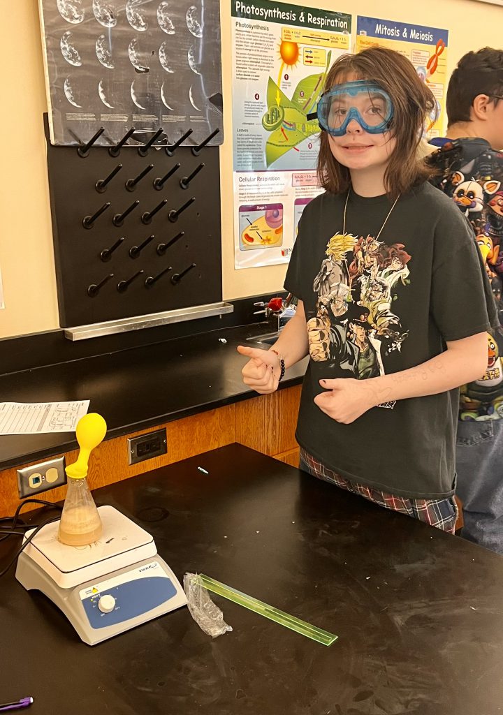 A student shows two thumbs up when watching the balloon inflate over the flask.