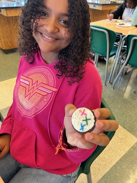 Girl holds cookie with sprinkles on it to show mitosis in action