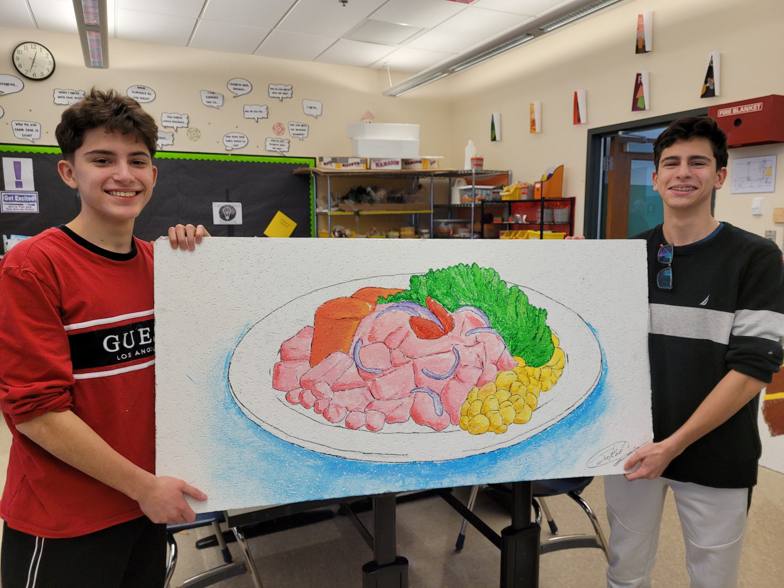 Students stand with a painted ceiling tile.