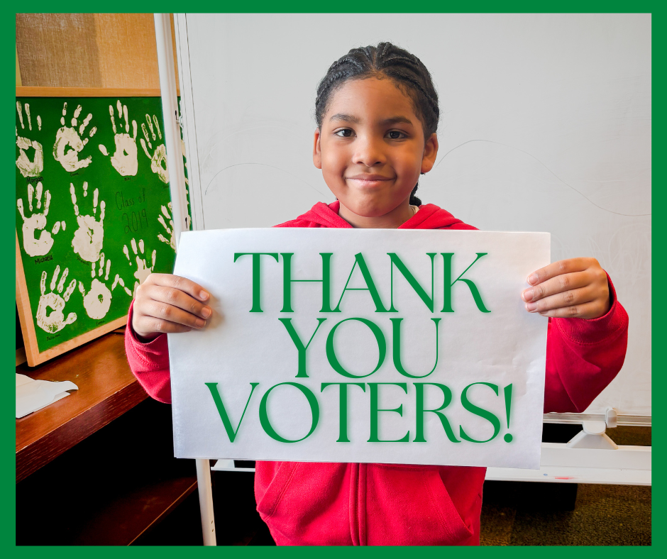 Smiling child in red sweatshirt holds sign that says Thank You Voters